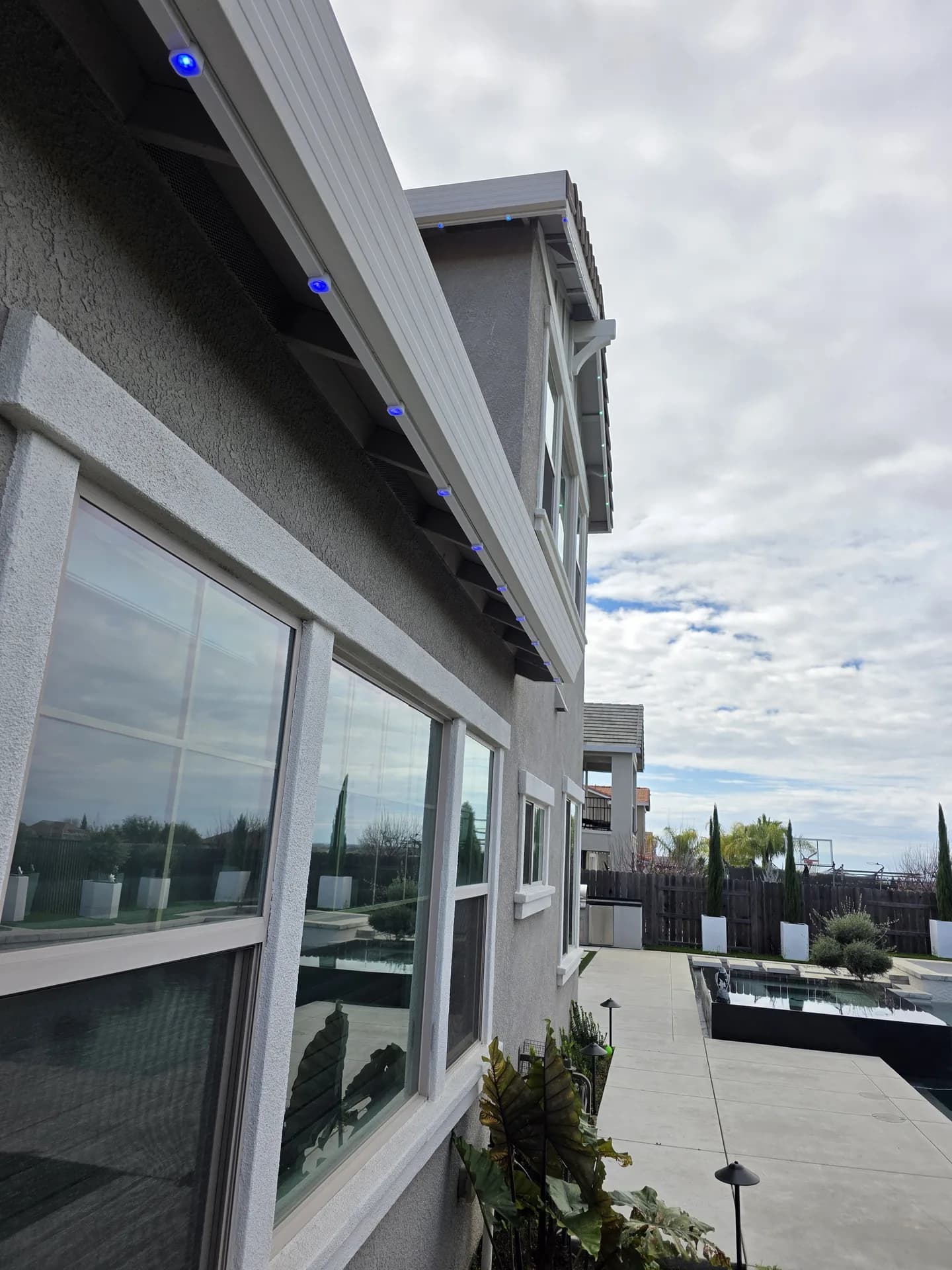 Permanent LED holiday lights installed along a rear soffit, low profile by day