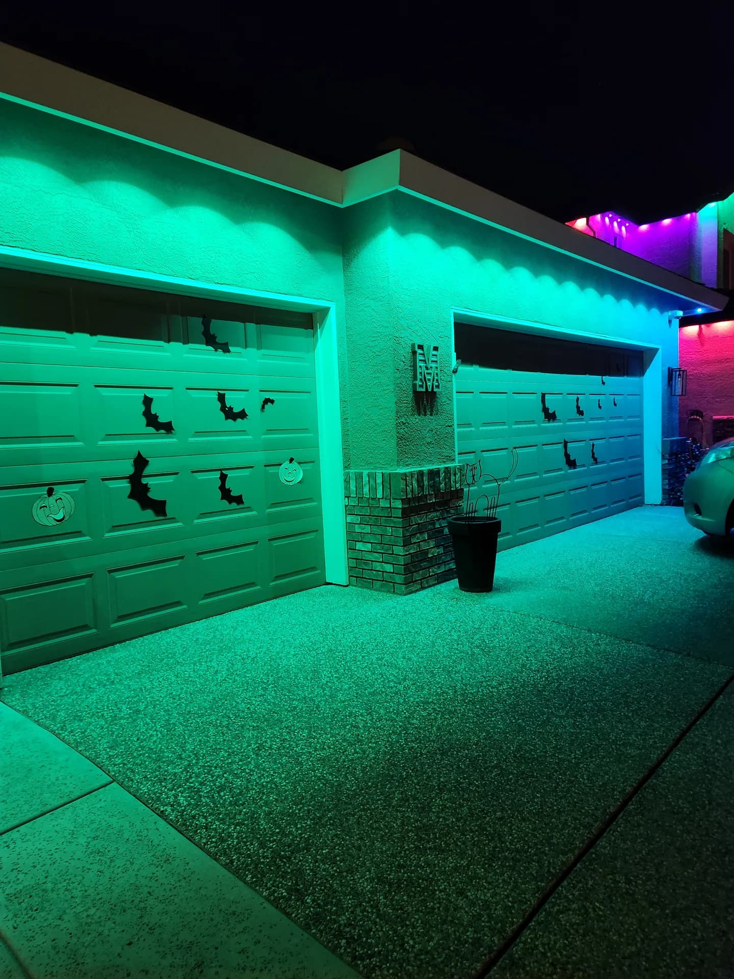 Permanent LED holiday lights in Halloween green on a garage and porch