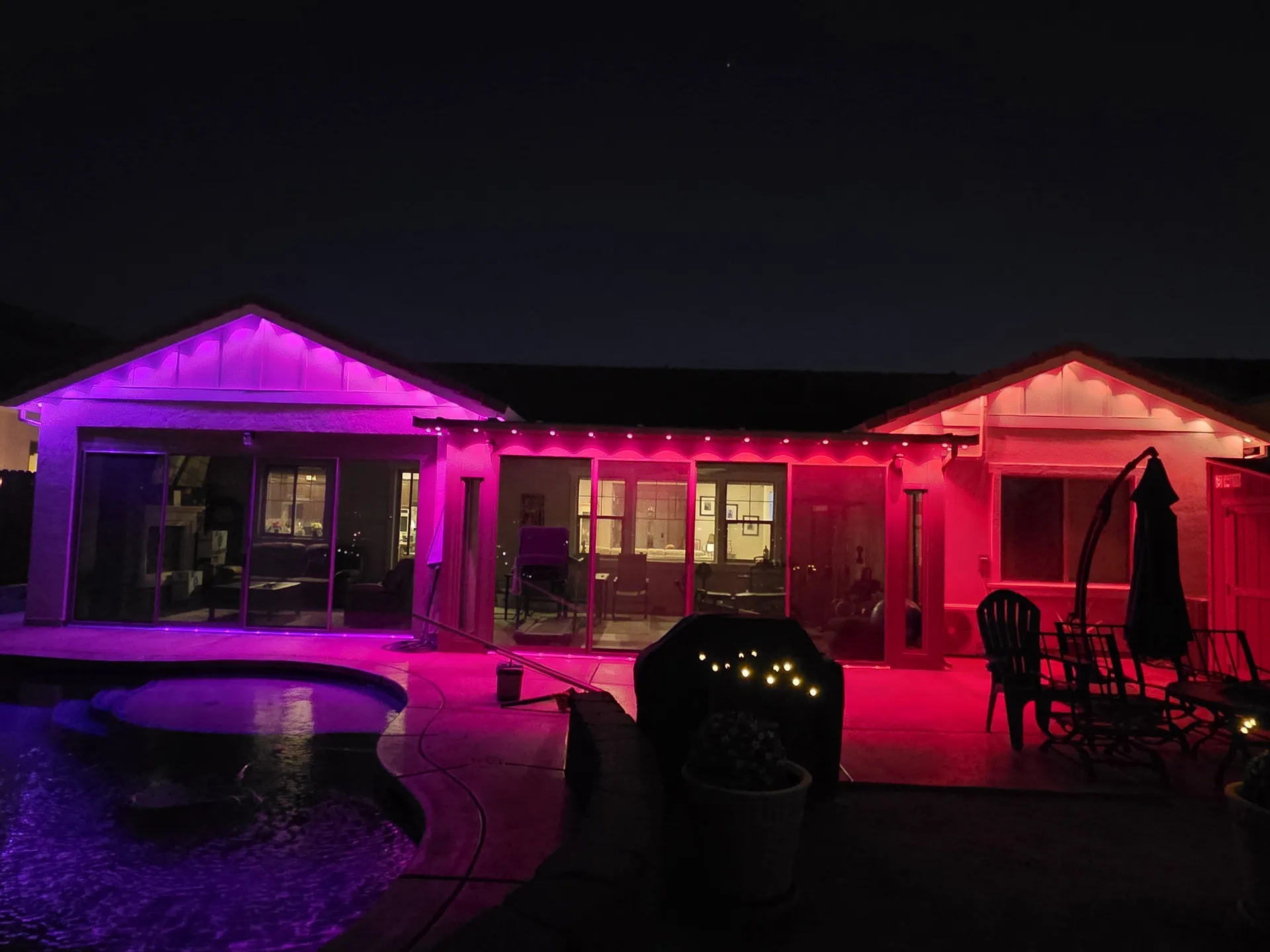 Permanent color Christmas lights on a backyard patio and pool house