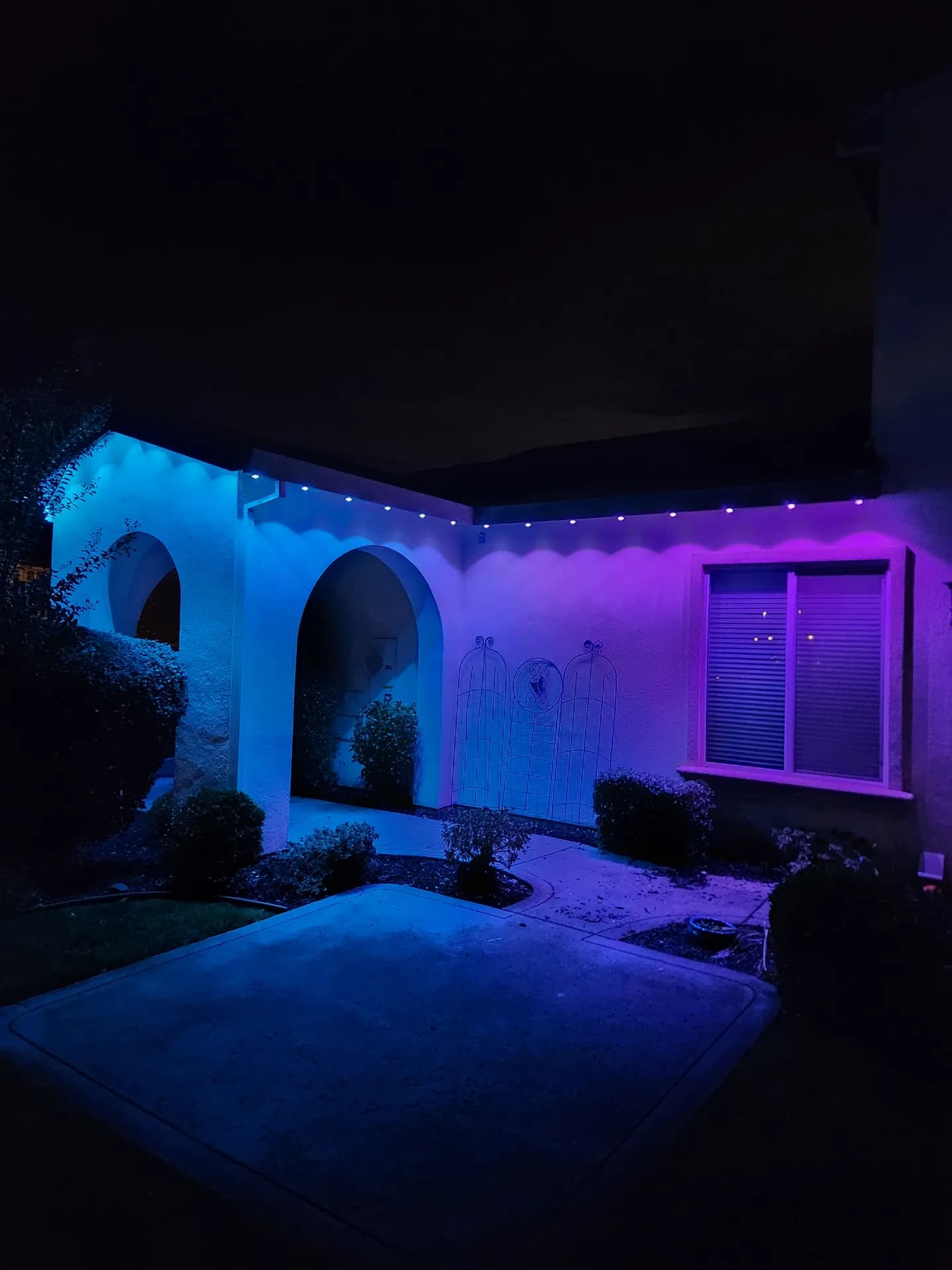 Permanent RGB holiday lights on a stucco entry with an arched porch