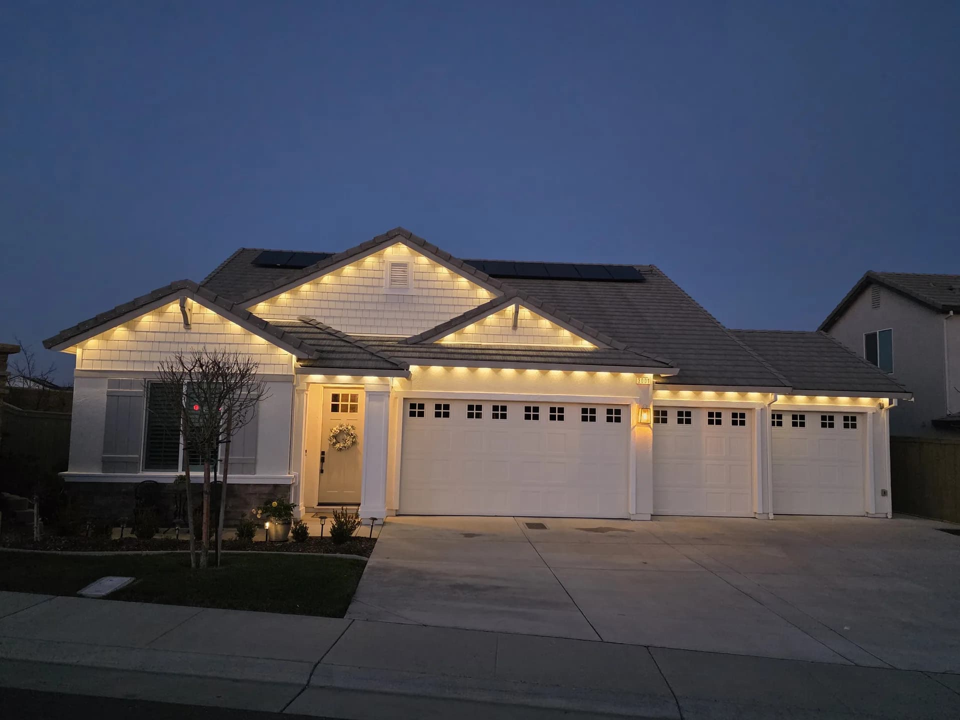 Permanent warm-white Christmas lights on a craftsman home at dusk in Rocklin, CA
